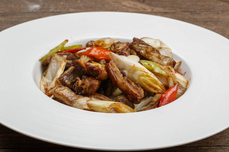 白色瓷盘装的葱爆羊五花肉图片