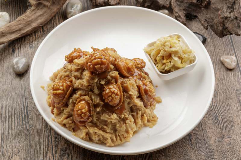 白色圆盘装的土豆焖鲍鱼摆放在樟木砧板上图片