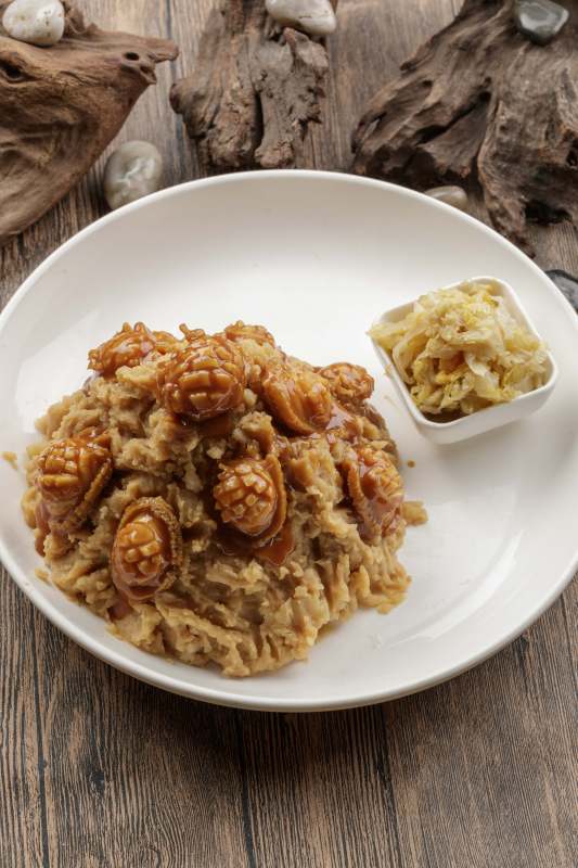 白色圆盘装的土豆焖鲍鱼摆放在樟木砧板上图片