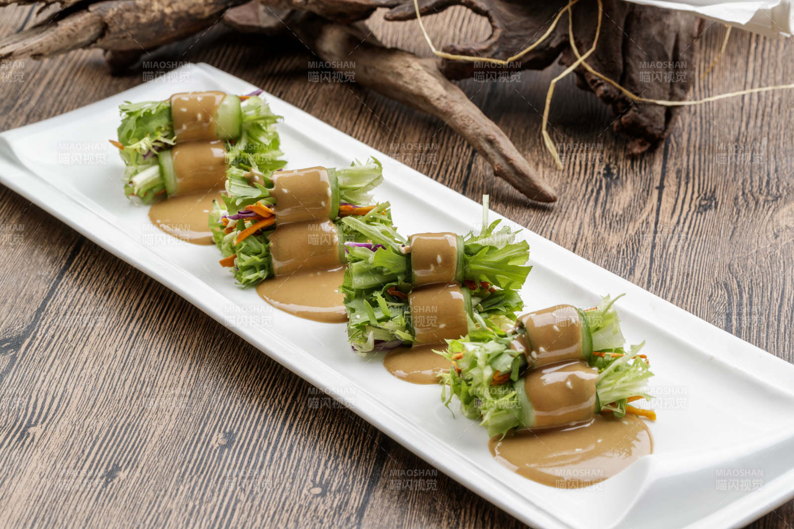 白色瓷盘装的芝麻酱乳瓜卷苦菊图片