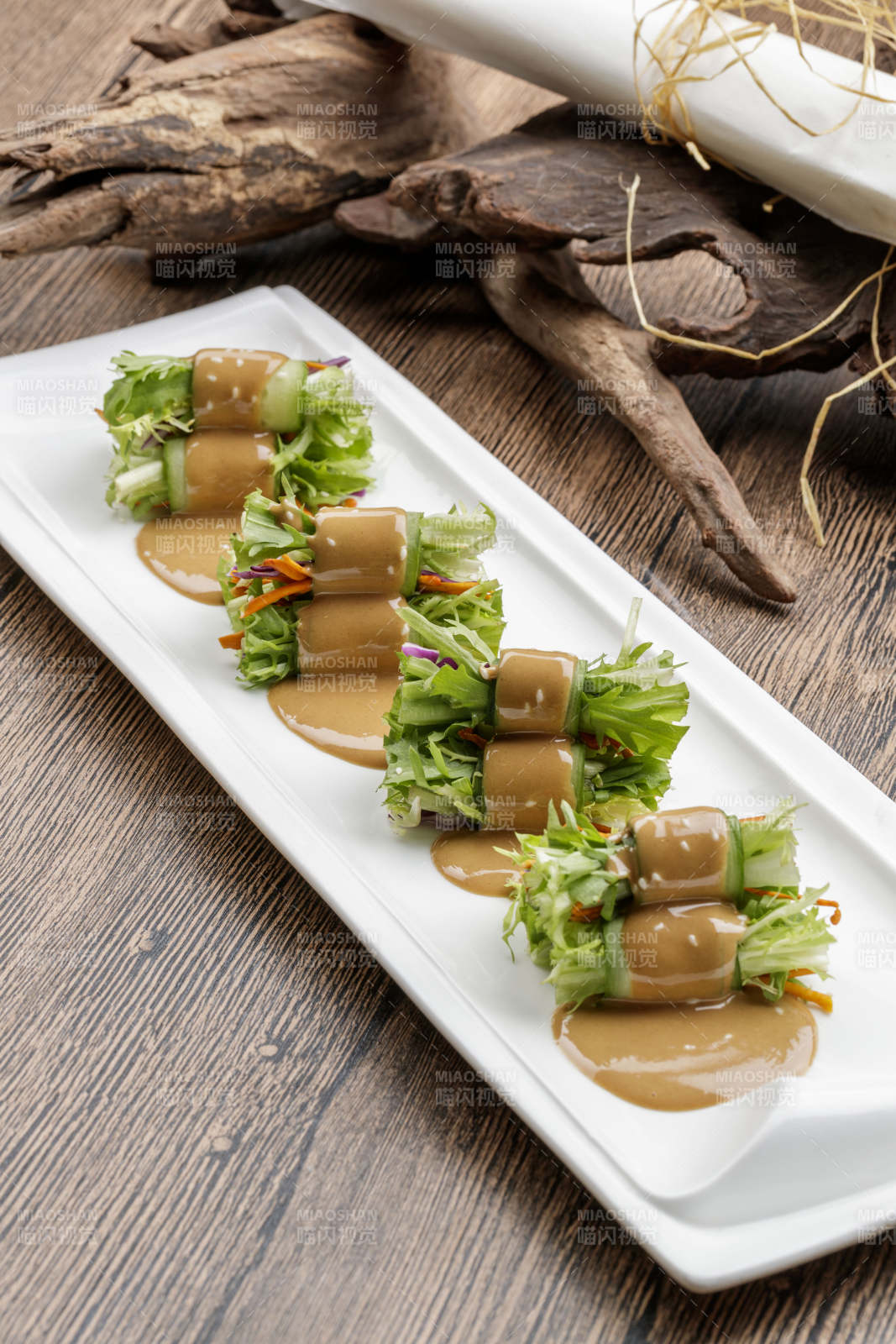 白色瓷盘装的芝麻酱乳瓜卷苦菊图片