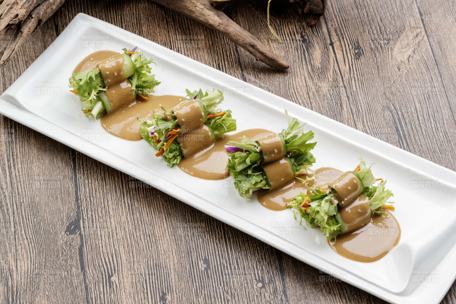 白色瓷盘装的芝麻酱乳瓜卷苦菊图片