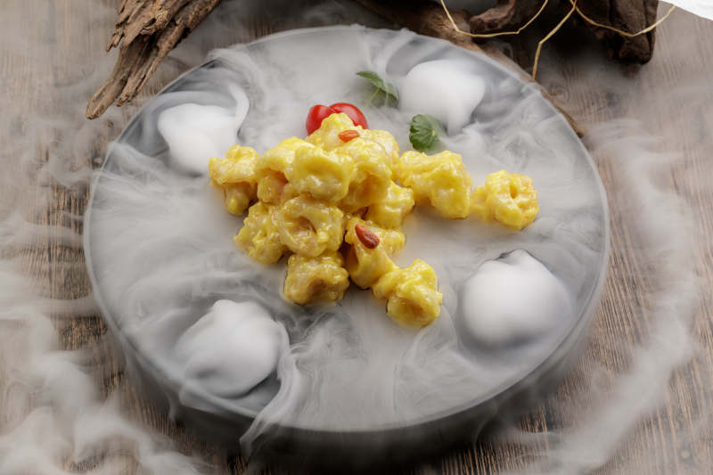 干冰缭绕的餐具摆放的芥香焗虾球图片