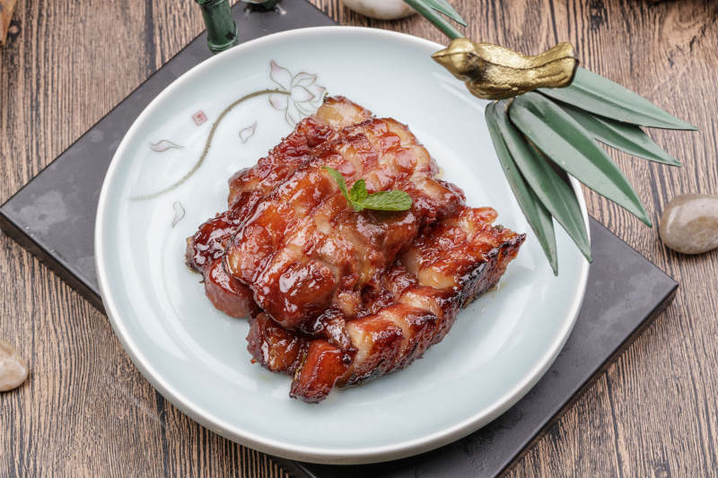 米花色瓷盘装的蜜汁叉烧肉摆放在樟木砧板上图片