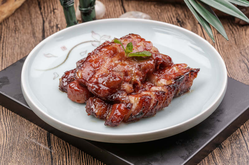 米花色瓷盘装的蜜汁叉烧肉摆放在樟木砧板上图片