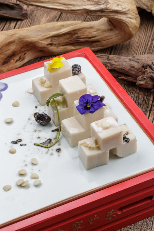 圆形黑色石盘装的奶香杏仁糕摆放在寿司帘上图片