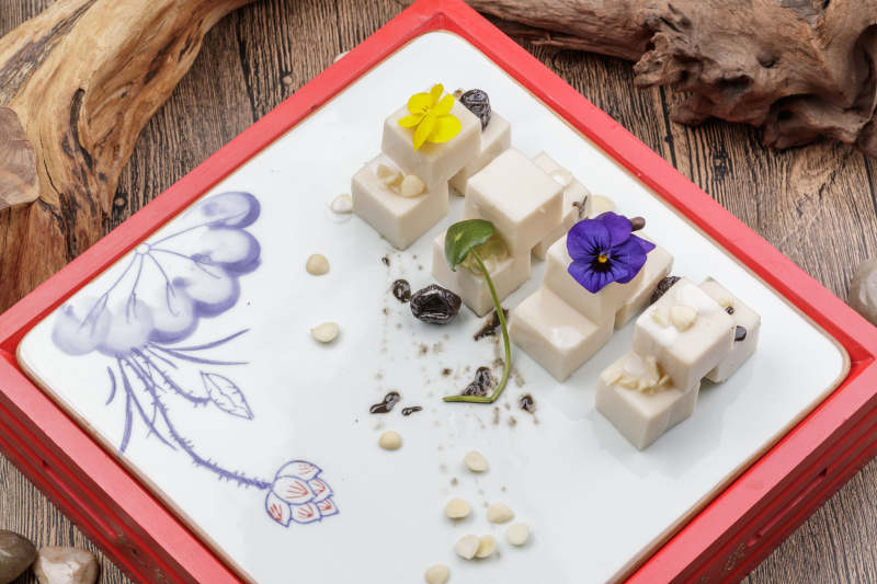 圆形黑色石盘装的奶香杏仁糕摆放在寿司帘上图片