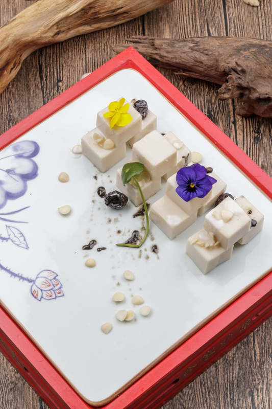 圆形黑色石盘装的奶香杏仁糕摆放在寿司帘上图片