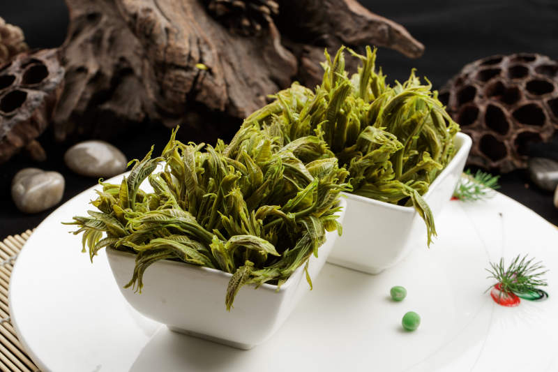 白色瓷盘装的盐水凉拌香椿苗图片