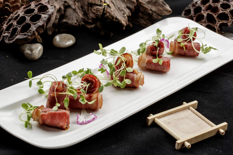 白色瓷盘装的香椿苗培根卷图片