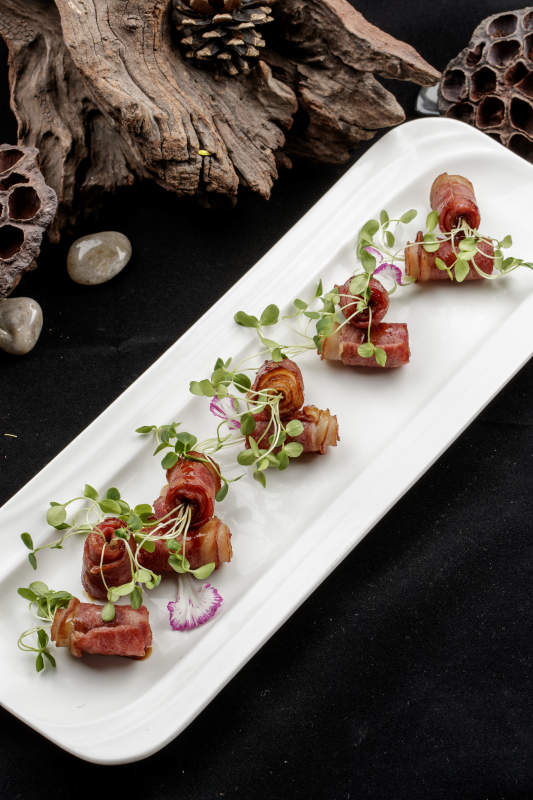 白色瓷盘装的香椿苗培根卷图片