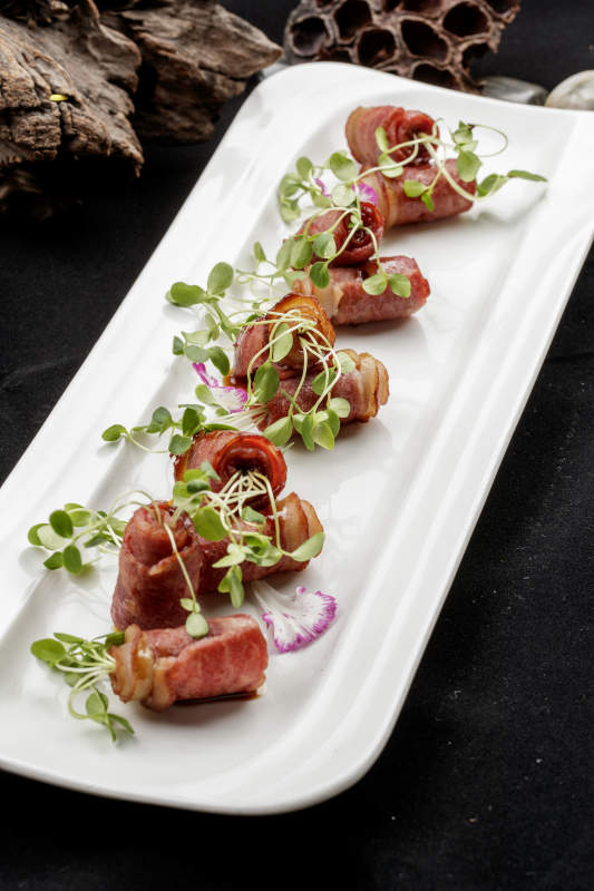 白色瓷盘装的香椿苗培根卷图片