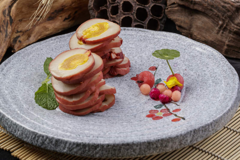 鱿鱼卷海鸭蛋摆放在寿司帘上图片