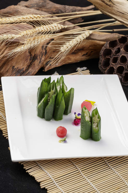 长方形瓷盘装的鲜秋葵摆放在寿司帘上图片