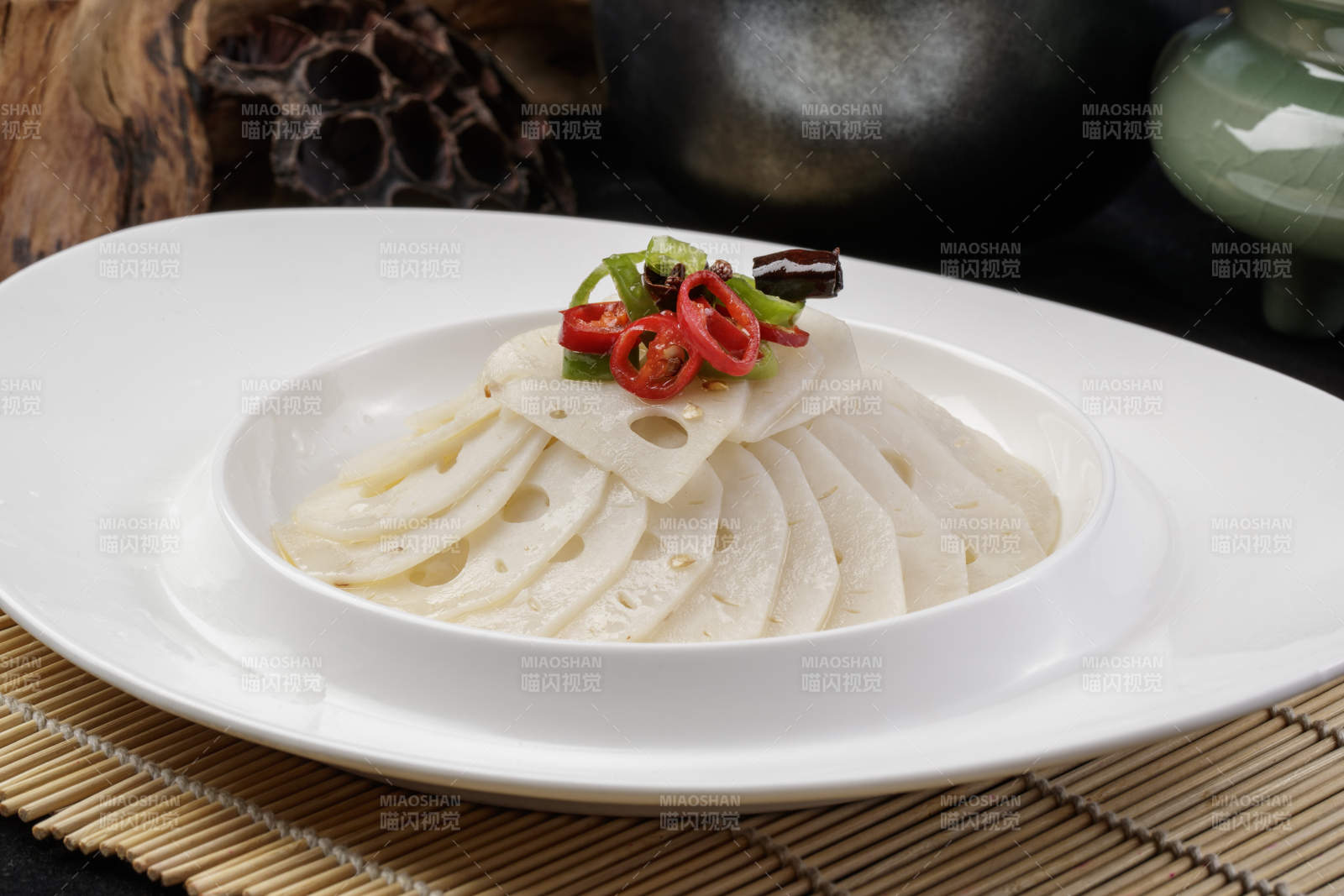 椭圆瓷盘装的蘸汁鲜藕摆放在寿司帘上图片