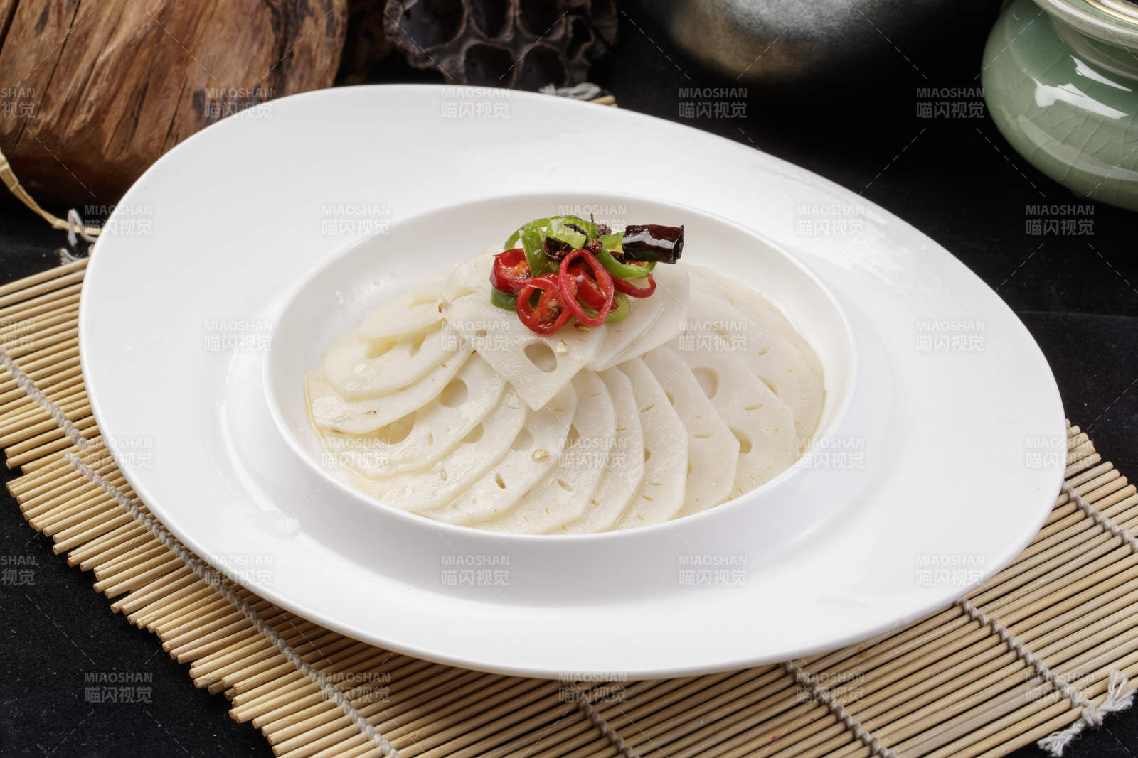 椭圆瓷盘装的蘸汁鲜藕摆放在寿司帘上图片