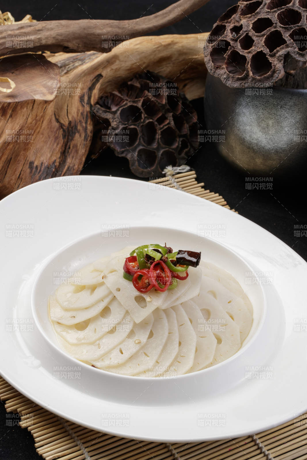 椭圆瓷盘装的蘸汁鲜藕摆放在寿司帘上图片