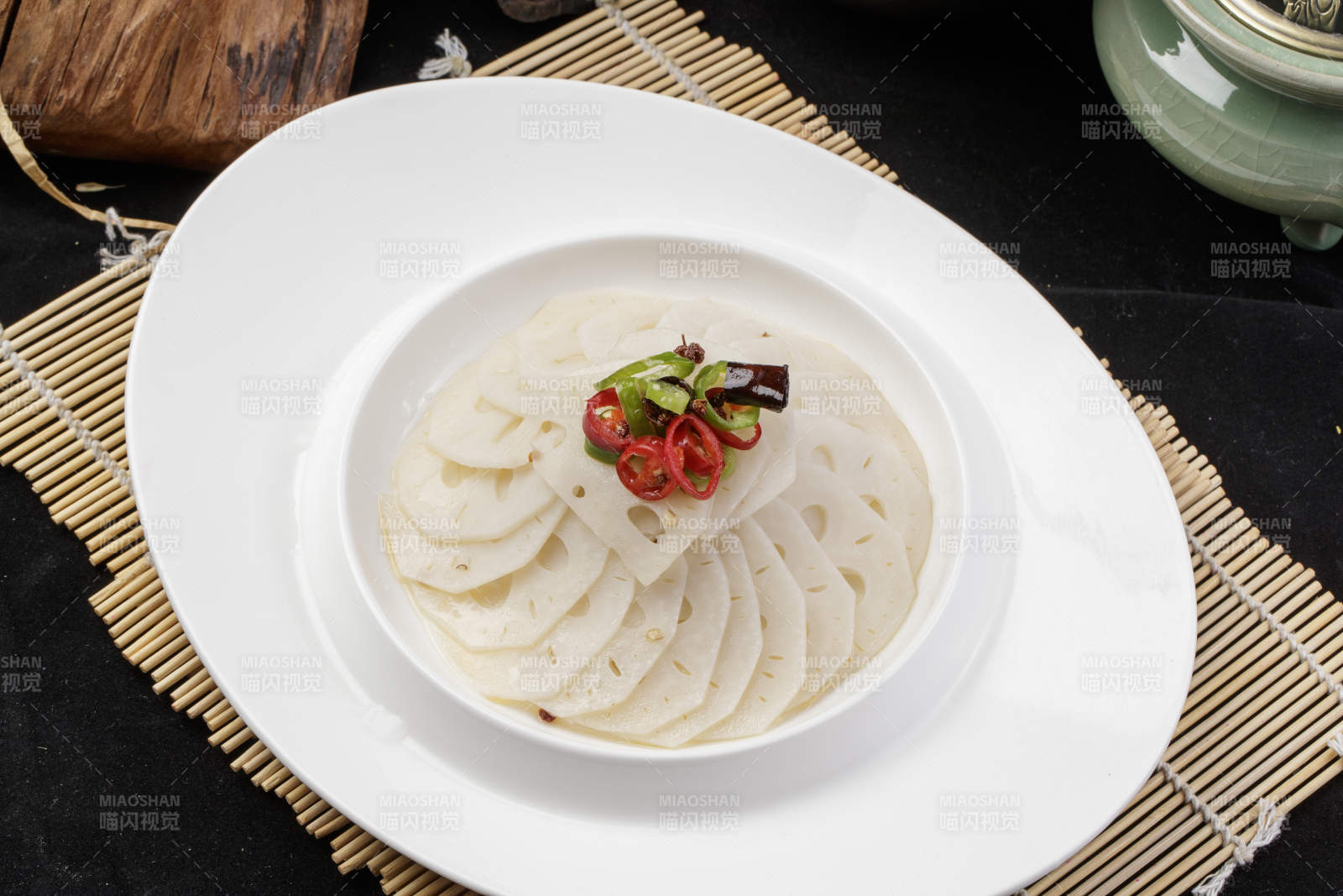 椭圆瓷盘装的蘸汁鲜藕摆放在寿司帘上图片