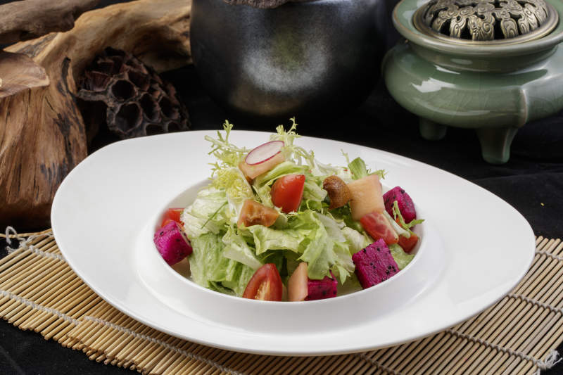 托圆瓷盘装的果蔬拌菜摆放在寿司帘上图片