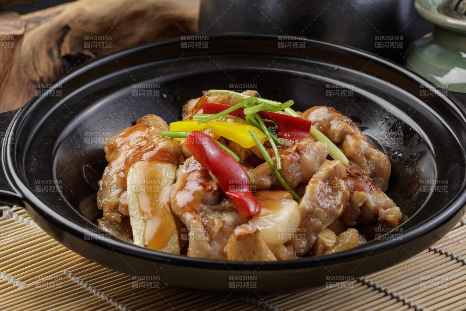 黑色砂锅装的蒜香砂锅鸡腿肉摆放在寿司帘上图片