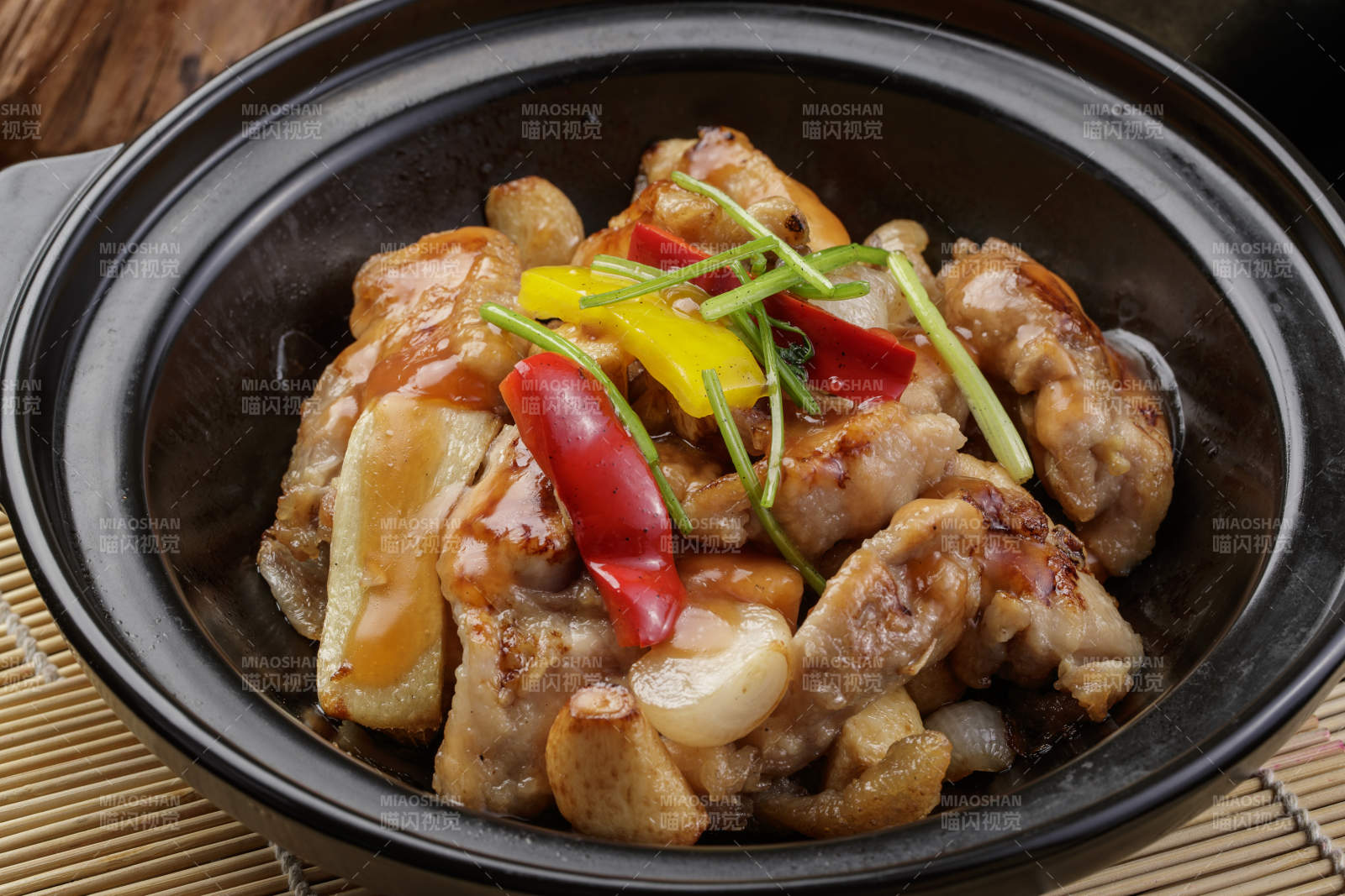 黑色砂锅装的蒜香砂锅鸡腿肉摆放在寿司帘上图片