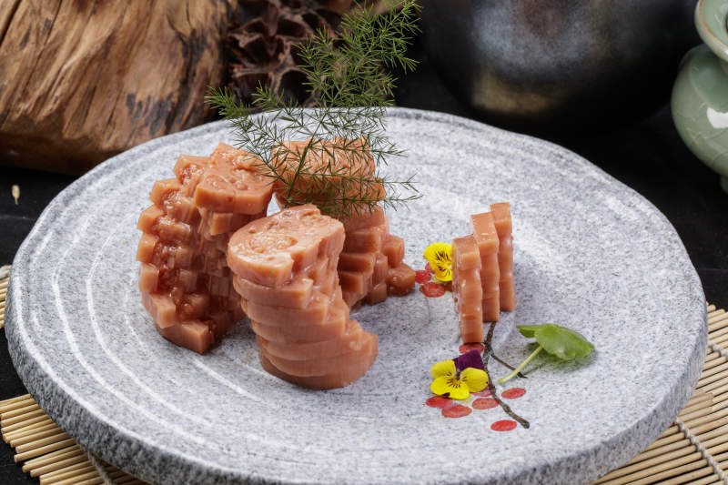 灰色螺旋瓷盘装的蜂蜜黄米藕摆放在寿司帘上图片