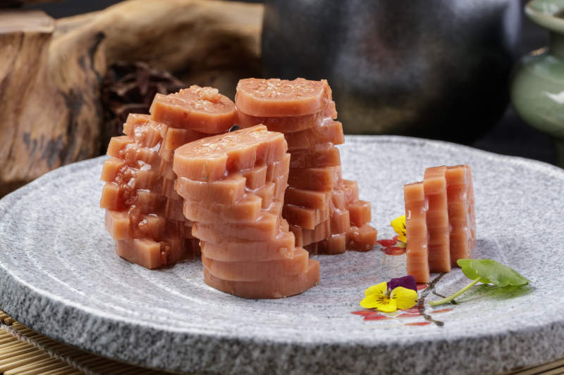 灰色螺旋瓷盘装的蜂蜜黄米藕摆放在寿司帘上图片