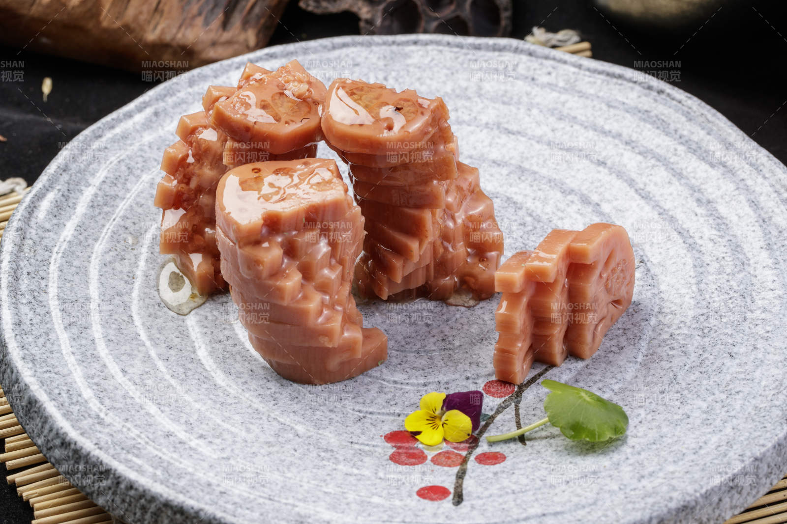 灰色螺旋瓷盘装的蜂蜜黄米藕摆放在寿司帘上图片