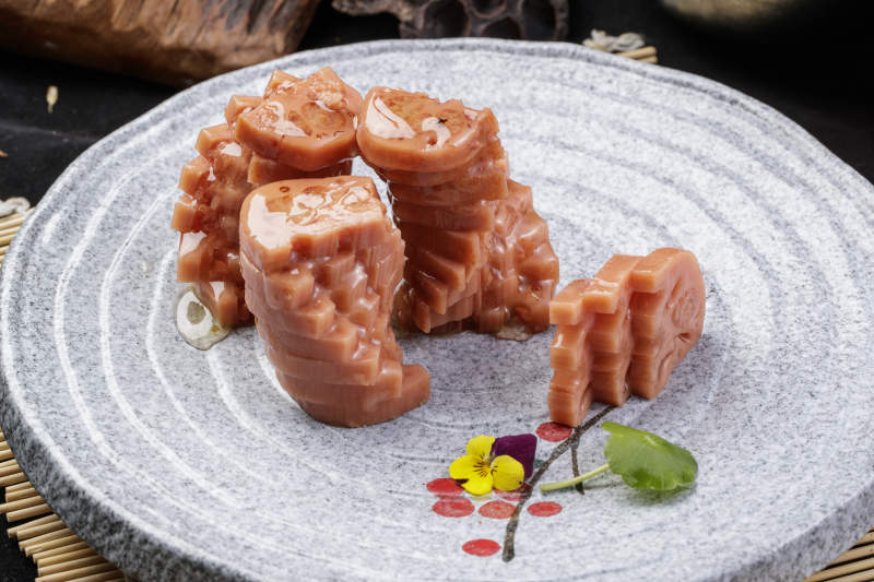 灰色螺旋瓷盘装的蜂蜜黄米藕摆放在寿司帘上图片