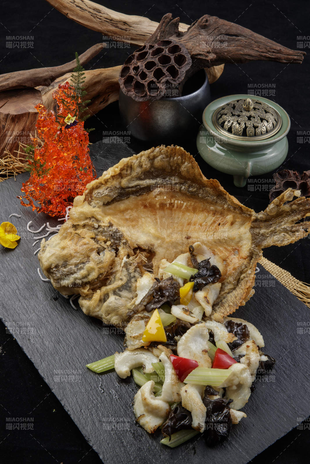 黑色石板装的两吃香酥多宝鱼摆放在黑色背景上图片