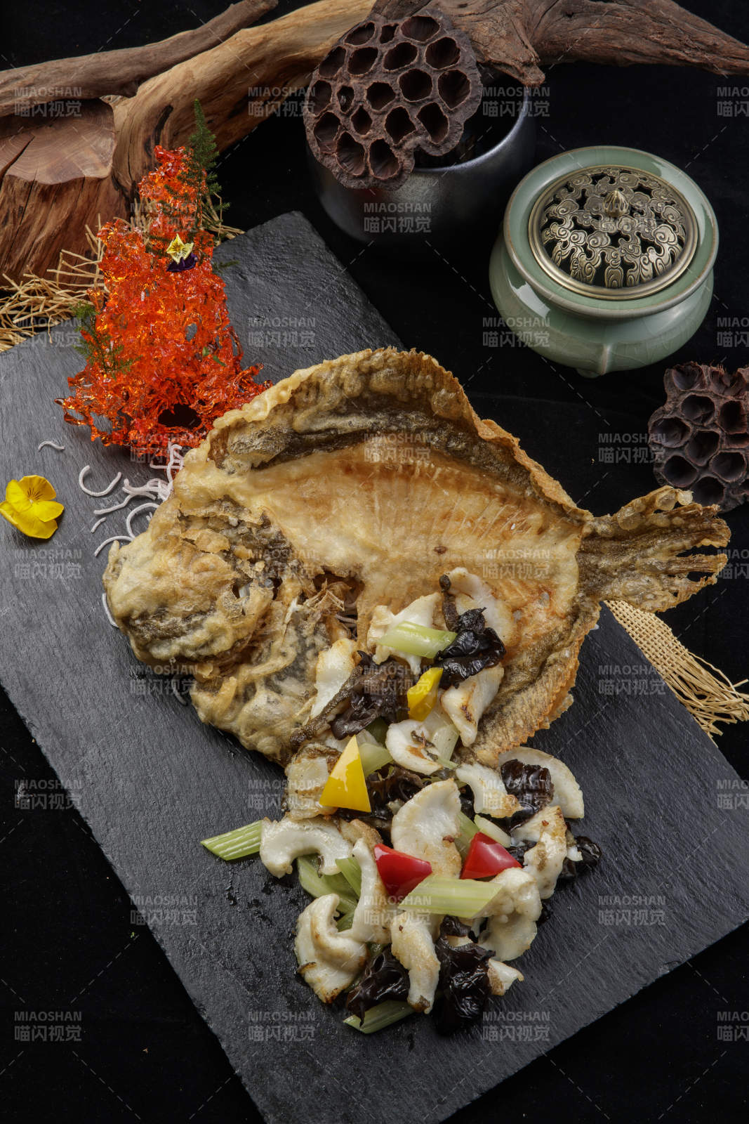 黑色石板装的两吃香酥多宝鱼摆放在黑色背景上图片