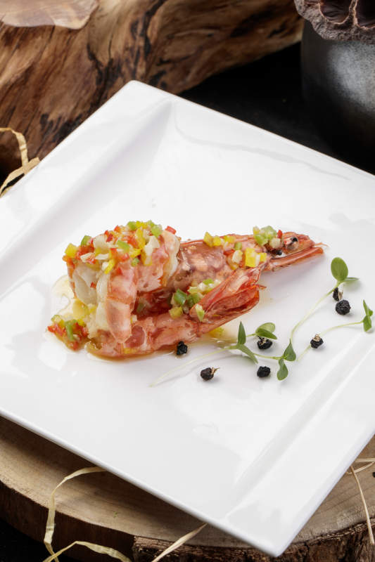 方形瓷盘装的开背大虾摆放在樟木砧板上图片