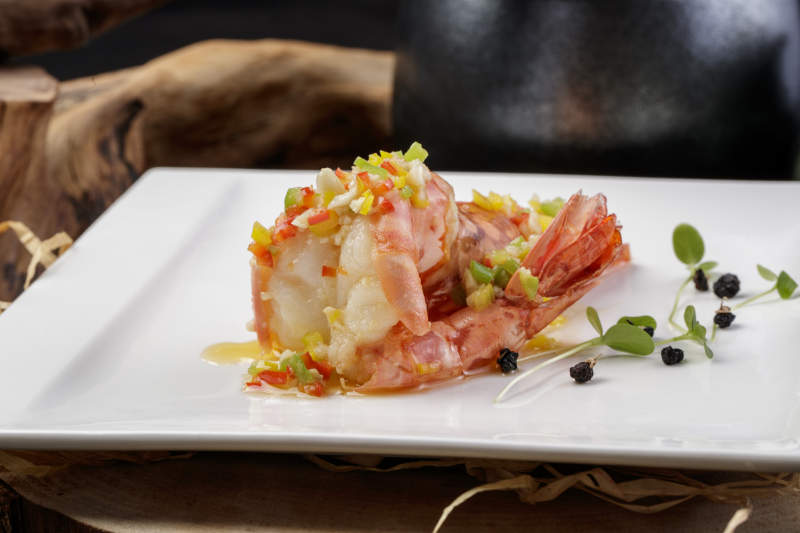 方形瓷盘装的开背大虾摆放在樟木砧板上图片