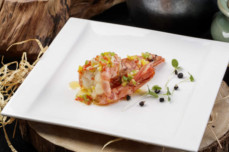 方形瓷盘装的开背大虾摆放在樟木砧板上图片