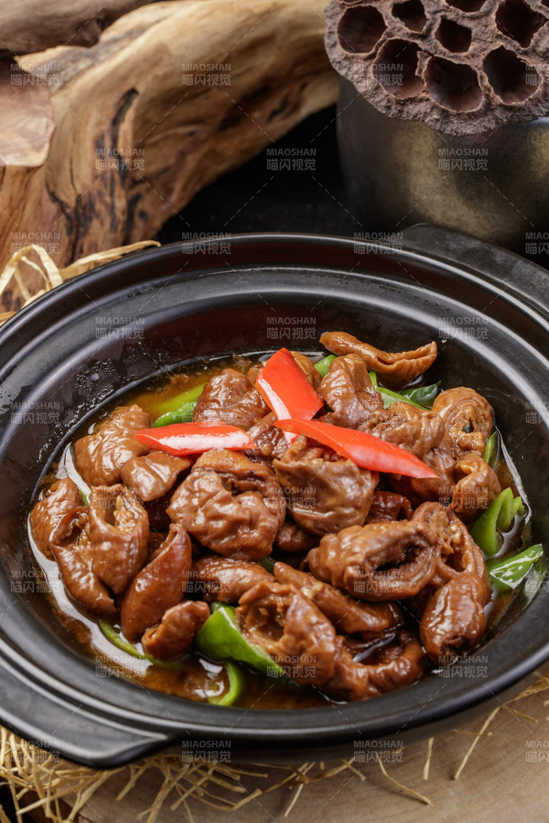 黑色砂锅装的砂锅肥肠摆放在麻布垫子上图片