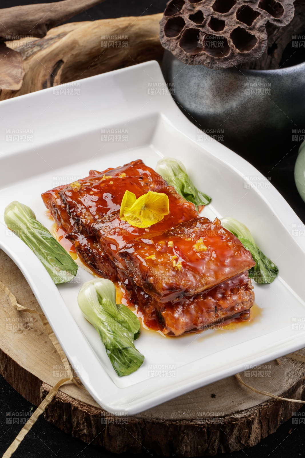 长方形瓷盘装的红烧带鱼段摆放在樟木砧板上图片