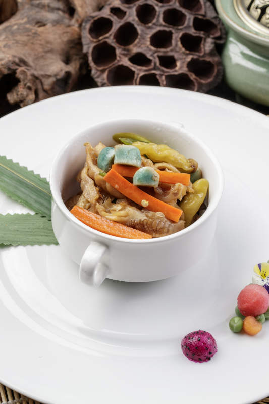 圆形瓷盘装的腊八蒜山椒凤爪摆放在寿司帘上图片