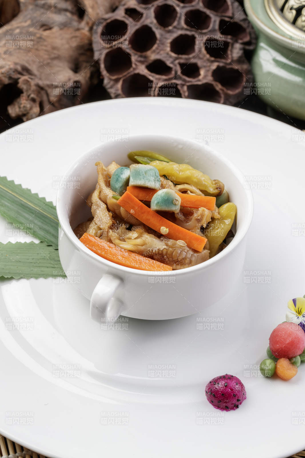 圆形瓷盘装的腊八蒜山椒凤爪摆放在寿司帘上图片