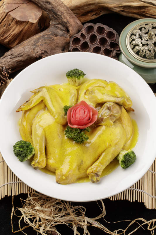 圆形瓷盘装的清蒸三黄鸡摆放在寿司帘上图片