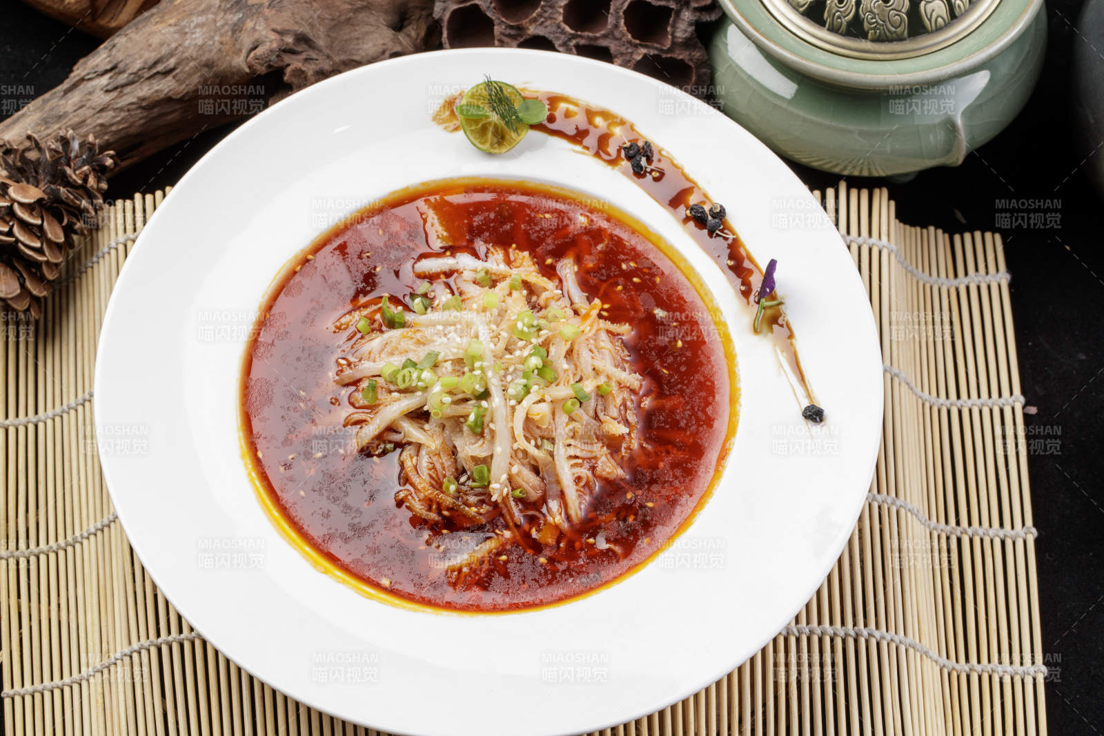 圆形瓷盘装的红油肚丝摆放在寿司帘上图片