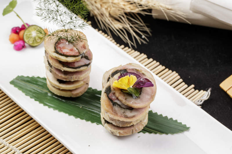 长方形瓷盘装的猪肉海苔香肠卷摆放在寿司帘上图片