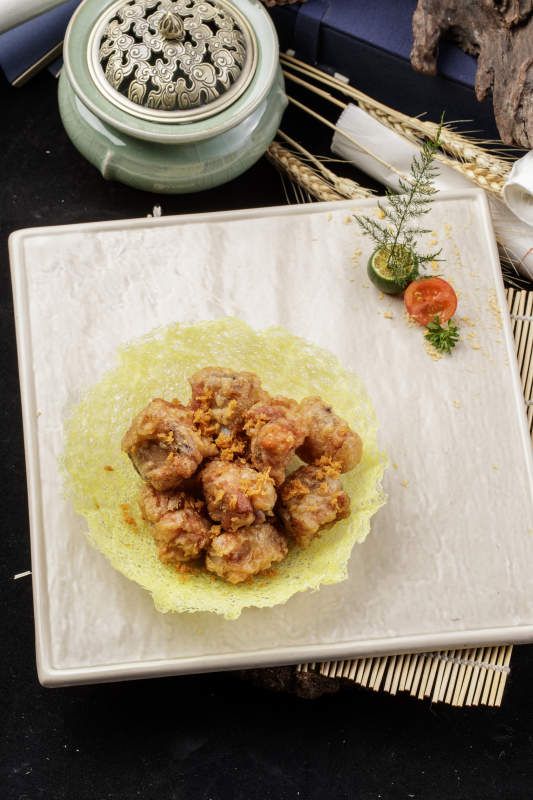 米色放瓷盘装的金盏猪小排摆放在寿司帘上图片