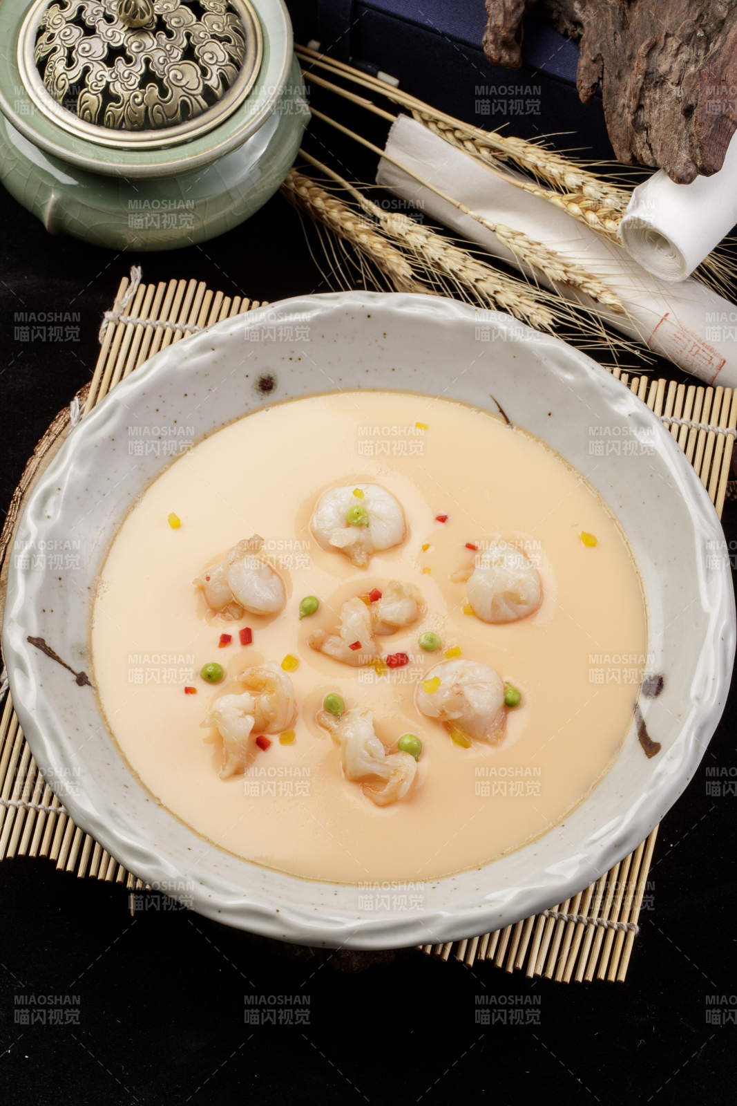 米色圆盘装的虾仁蒸水蛋摆放在寿司帘上图片