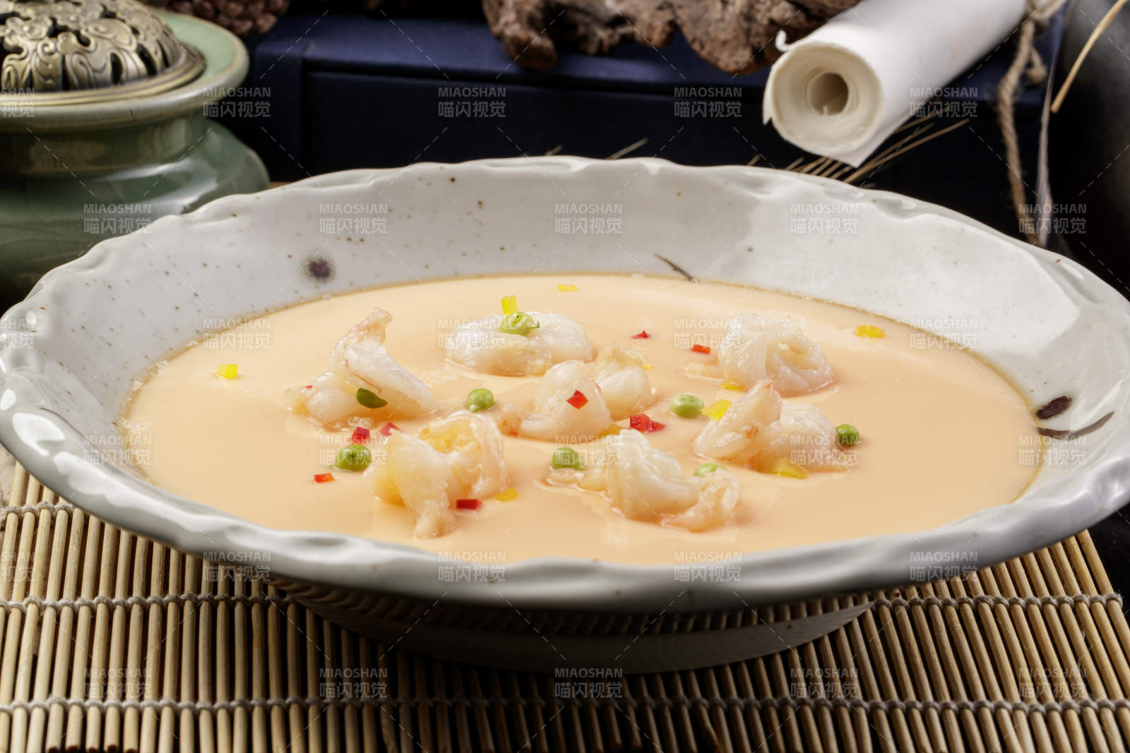 米色圆盘装的虾仁蒸水蛋摆放在寿司帘上图片