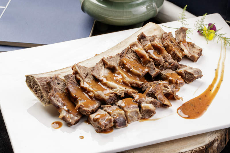 黑胡椒酱汁牛肋剔骨肉摆放在樟木砧板上图片