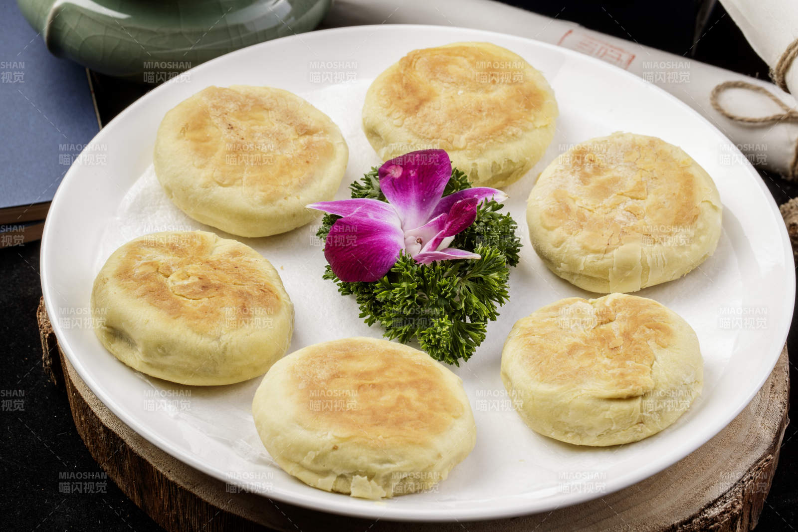 圆形瓷盘装的咸鱼酥饼摆放在樟木砧板上图片
