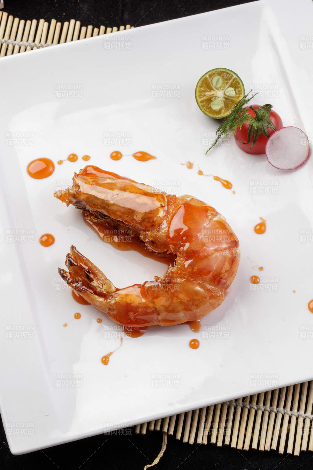 方形瓷盘装的油煎浇汁深海虾摆放在寿司帘上图片