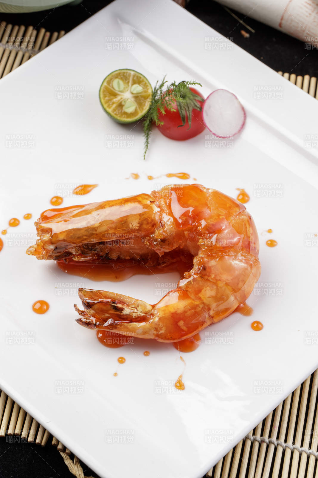方形瓷盘装的油煎浇汁深海虾摆放在寿司帘上图片