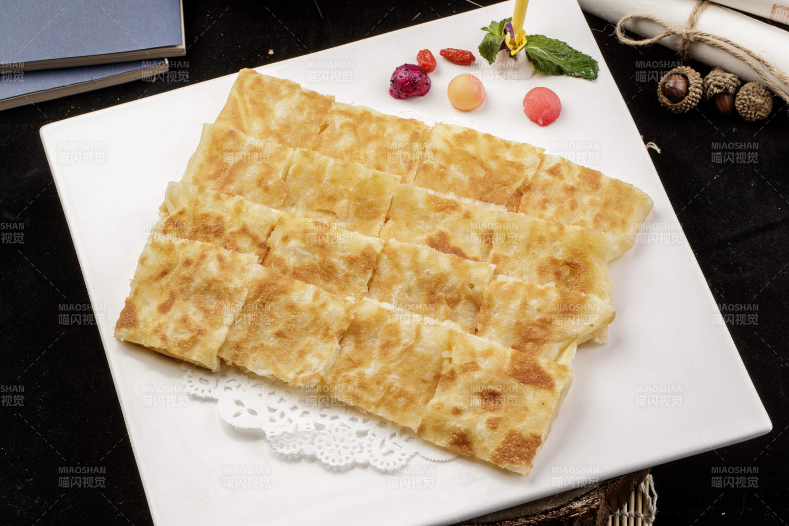 方形瓷盘装的印度飞饼摆放在樟木砧板上图片