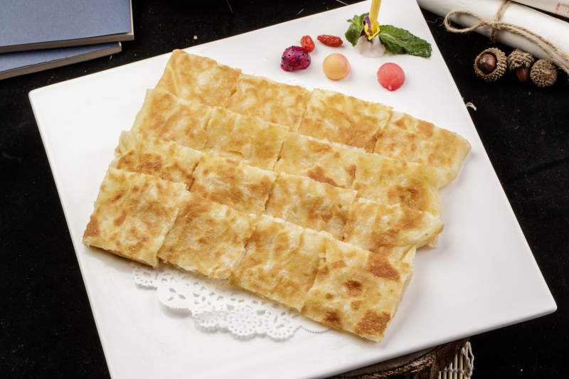 方形瓷盘装的印度飞饼摆放在樟木砧板上图片